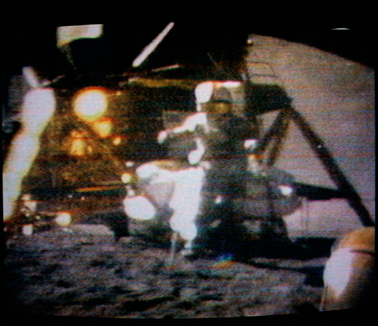 A television image of an astronaut in a spacesuit standing on the lunar surface.